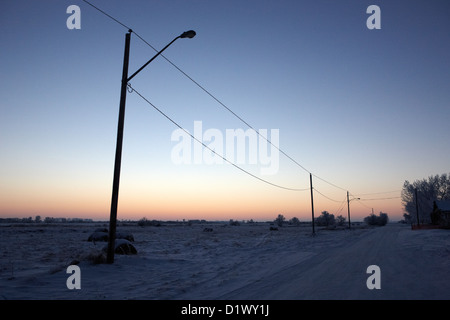sun setting over rural snow covered scene in remote village of Forget Saskatchewan Canada Stock Photo