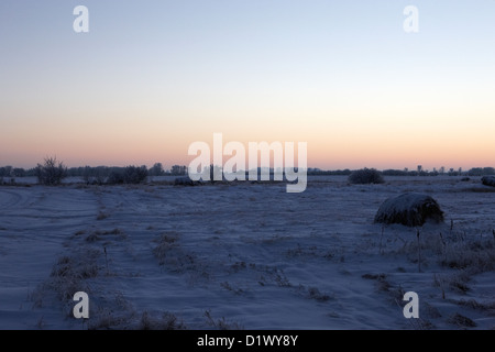 sun setting over rural snow covered scene in remote village of Forget Saskatchewan Canada Stock Photo