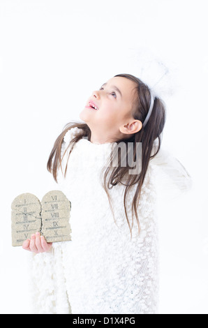 A little girl dressed as angel holding ten commandments Stock Photo