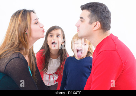 Mom and Dad kissing and two children staring at them Stock Photo