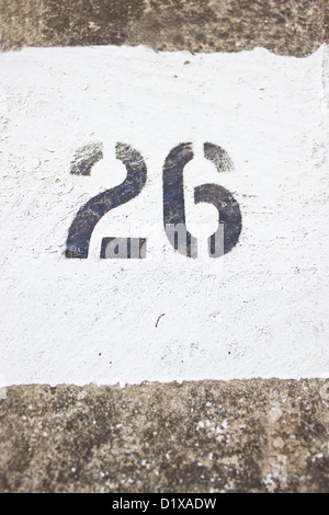 Number 26 on concrete wall with white painting. Stock Photo
