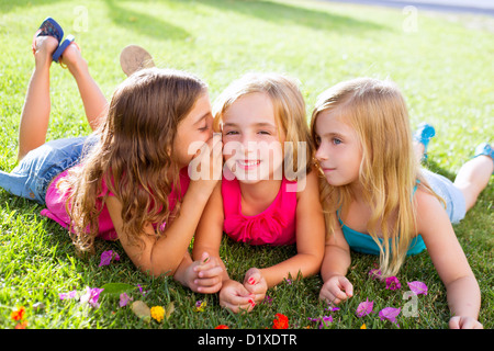 children friend girls group playing whispering on flowers grass in vacations Stock Photo