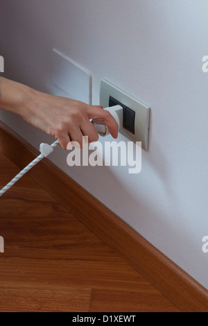 hand putting the plug into a power outlet Stock Photo
