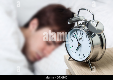 Close up of an old fashioned alarm clock, young man asleep Stock Photo