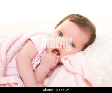 baby girl with toothache in pink with winter white fur background Stock Photo