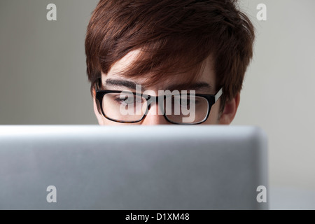 Young man wearing glasses looking at a computer screen. Stock Photo