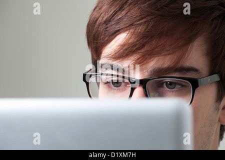 Young man wearing glasses looking at a computer screen. Stock Photo