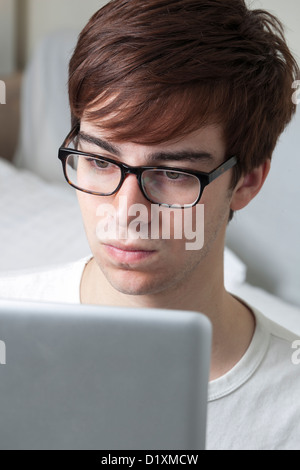 Young man wearing glasses looking at a computer screen. Stock Photo