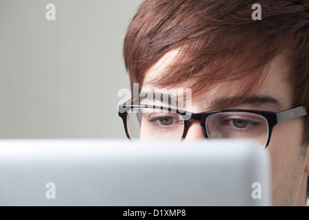 Young man wearing glasses looking at a computer screen. Stock Photo