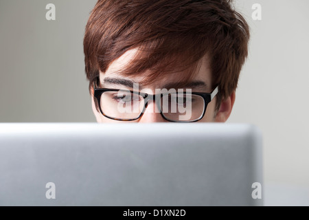 Young man wearing glasses looking at a computer screen. Stock Photo