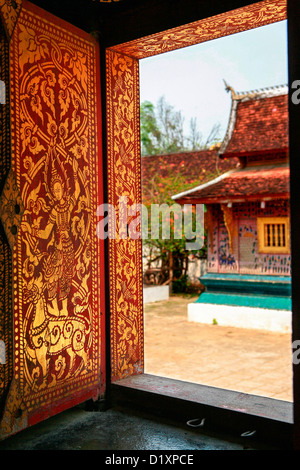 View of La Chapelle Rouge through a decorated doorway at Wat Xieng Thong in Luang Prabang, Northern Laos, Southeast Asia.