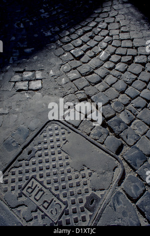 Section of an old cobbled street with drain cover Stock Photo