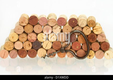 Vintage corkscrew against of the stack of wine corks with reflection on the glass table Stock Photo