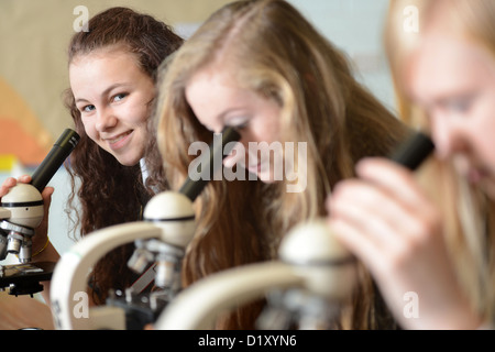 School girls using microscopes during a science lesson at Pates Grammar School in Cheltenham, Gloucestershire UK Stock Photo