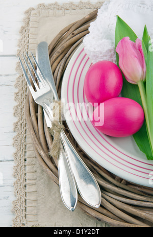 Easter dinner setting with two pink eggs and tulip, rustic white wooden background Stock Photo