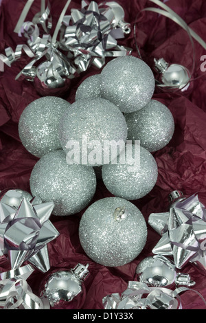 Silver glitter baubles with bows and ribbon on a red background. Stock Photo