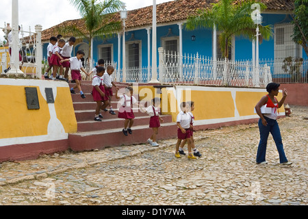 Uniformed schoolchildren marching along street Stock Photo