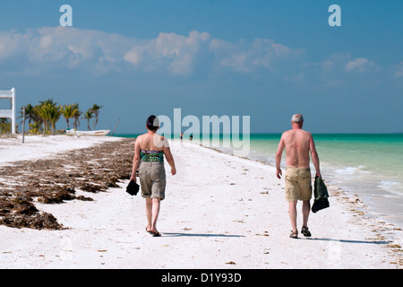 Older couple strolling on a white sand beach in Isla Holbox, Mexico. Stock Photo