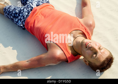Image of a handsome guy in vest relaxing on sand Stock Photo