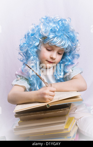 little girl with blue hair writing with quill pen in book Stock Photo