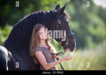 Frederiksborger. Smiling young woman holding black stallion Stock Photo