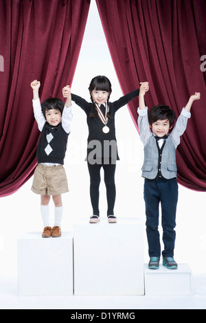 kids standing on podium raising their hands Stock Photo