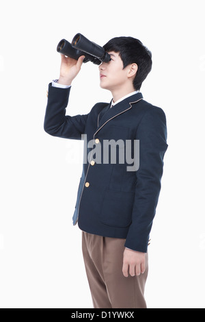 a male student with school uniform looking through a binocular Stock Photo