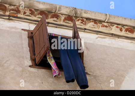 Laundry hanging in front of an old window with shutters in the medieval town Gruissan in southern France Stock Photo