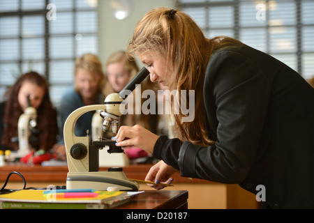 School girls using microscopes during a science lesson at Pates Grammar School in Cheltenham, Gloucestershire UK Stock Photo