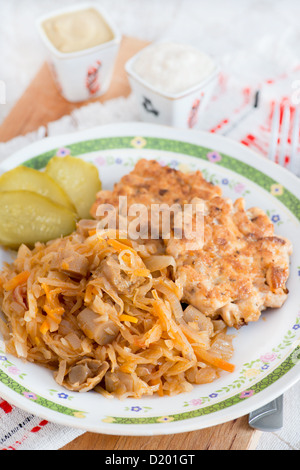 Stewed cabbage with mushrooms, chicken cutlets on side Stock Photo