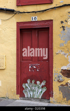 Painted doorway, Funchal, Madeira, red door, with yellow orange paster surround plus waving hands Stock Photo