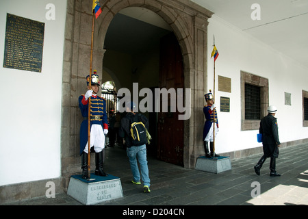 Smart Presidential guards nominally guard the entrance to the Presidential Palace in Quito, ignoring the backpacker heading in Stock Photo