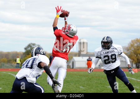 Football Receiver leaps in between defensive backs catching ball during a high school game. USA. Stock Photo