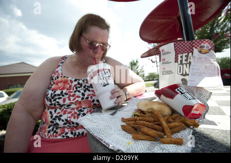 Aug. 2, 2012 - Marietta, GA - Overweight middle-aged woman eats high-fat lunch of cheeseburger, friends and soft drink at fast food restaurant near Atlanta. (Credit Image: © Robin Nelson/ZUMAPRESS.com) Stock Photo