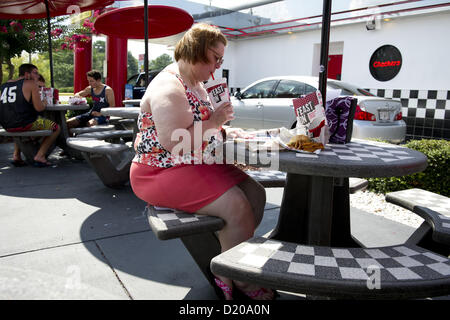 Aug. 2, 2012 - Marietta, GA - Overweight middle-aged woman eats high-fat lunch of cheeseburger, friends and soft drink at fast food restaurant near Atlanta. (Credit Image: © Robin Nelson/ZUMAPRESS.com) Stock Photo