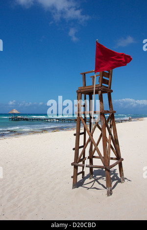 Empty lifeguard post with a red flag at a white, Caribbean beach under a clear sky. Stock Photo