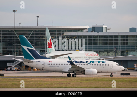 A Westjet Boeing 737 jetliner taxies by an Air Transat Airbus A330 ...