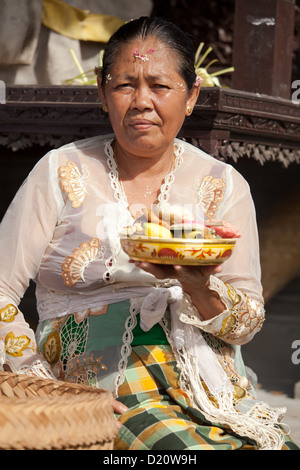 BALI - FEBRUARY 1. Priest's wife with fruit offering in temple for Galungan ceremony on February 1, 2012 in Bali, Indonesia. Stock Photo