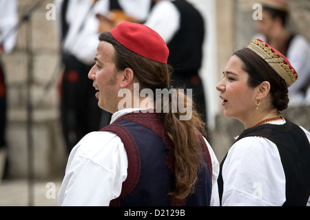 Young man and woman in national dress singing as part of a song / dance folk group at Cilipi. Stock Photo