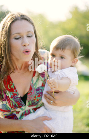 Young mother with her daugther, blowing a dandelion clock, Old Danube, Vienna, Austria Stock Photo