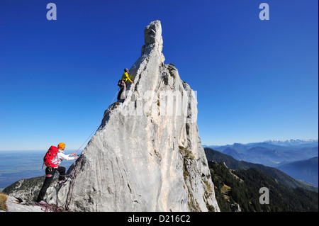 Young woman belaying climber at pinnacle, Kampenwand, Chiemgau Alps, Chiemgau, Upper Bavaria, Bavaria, Germany Stock Photo