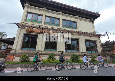 BALI - FEBRUARY 3. Young people cycling past starbucks coffee in Ubud on February 3, 2012 in Bali, Indonesia. Stock Photo