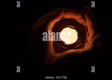 A pair of hands holding a lit candle. Stock Photo