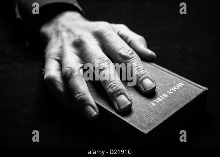 A black and white image of a mans hand holding the Holy Bible. Stock Photo