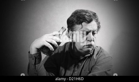 man turned away from the bottle of whiskey, which is held in the hand  Stock Photo