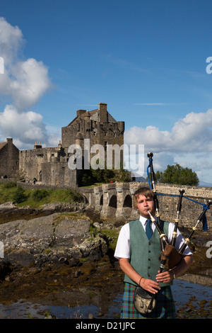 Young bagpiper in front of Eilean Donan Castle at Loch Duich, Near Dornie, Highland, Scotland, United Kingdom Stock Photo