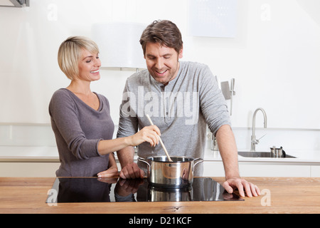 Germany, Bavaria, Munich, Mature couple cooking food in kitchen, smiling Stock Photo