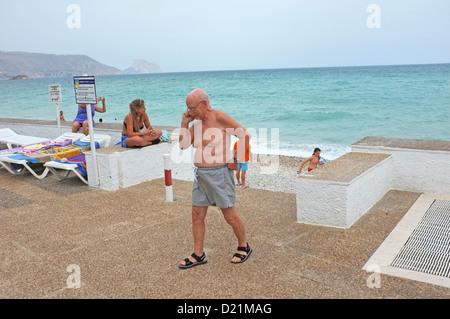 A old man using his phone by a beach in Spain Stock Photo
