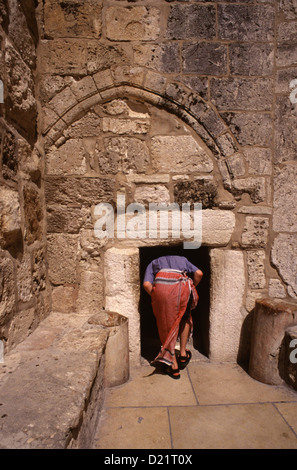 A tourist enters the 'Door of humility' at the Church of the Nativity, or Basilica of the Nativity, traditionally believed by Christians to be the birthplace of Jesus Christ in the West Bank town of Bethlehem in the Autonomous Palestinian Authority Israel Stock Photo