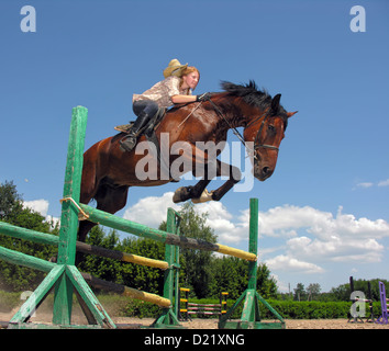 young cowgirl jumping with chestnut horse Stock Photo